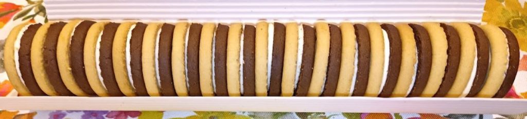 Fotografia di alcuni dolcetti formati da un biscotto alla vaniglia e uno al cacao uniti tra loro da uno strato di crema al latte. 